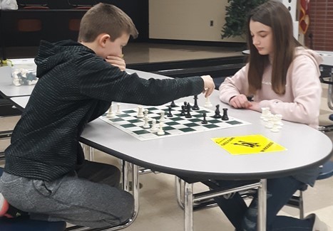Middle school chess match between an boy and girl.